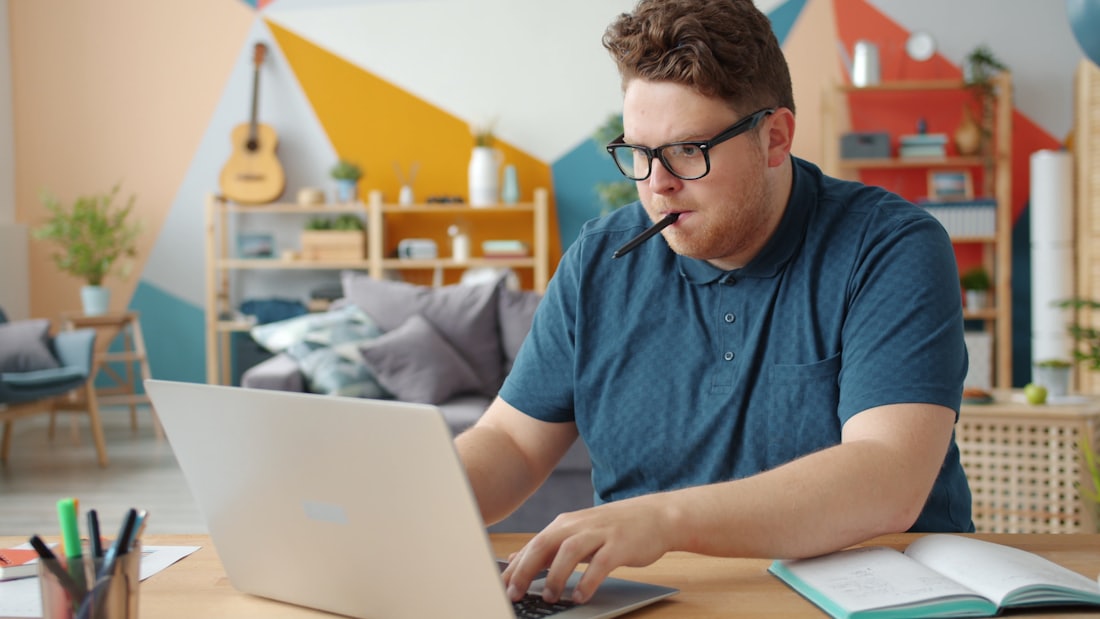 An intern taking notes beside a laptop.